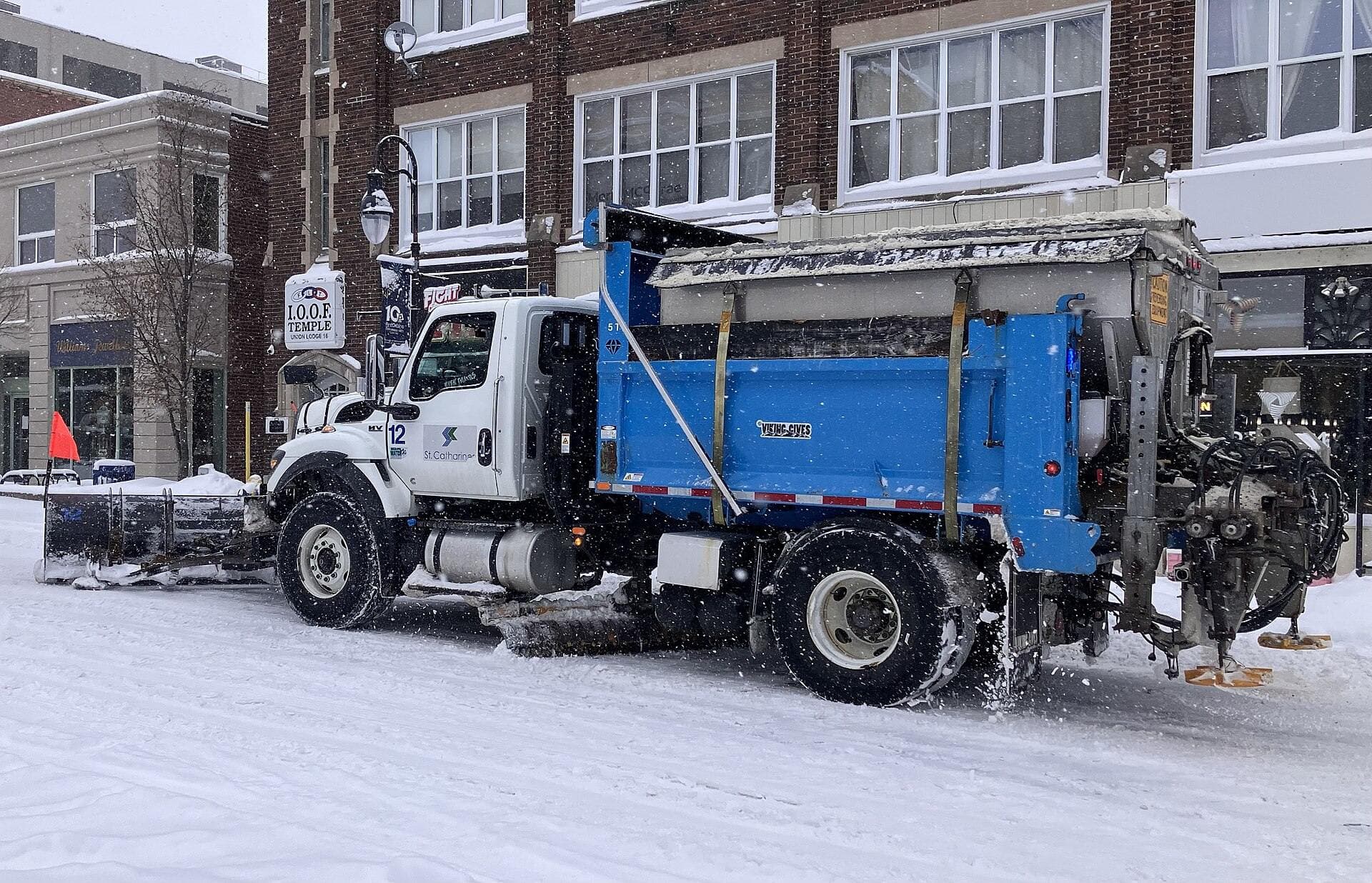 Plow truck clearing a snow-covered Ontario street during a heavy snowfall